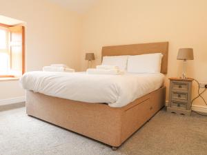una camera da letto con un letto grande con lenzuola bianche di The Cottage a Pwllheli