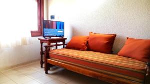 a couch with orange pillows and a television on a table at Complejo de Mar Wasiyki - Villa Gesell in Villa Gesell