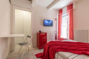 a bedroom with a red bed and a chair and a window at Suite Modena al Centro - Affitti Brevi Italia in Modena