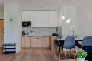 eine Küche mit weißen Schränken und einem Tisch und Stühlen in der Unterkunft VacationClub Marina Rogowo Apartament 56 in Rogowo