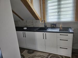 a white kitchen with a sink and a window at Viktor Lux Apartmani 7 in Soko Banja