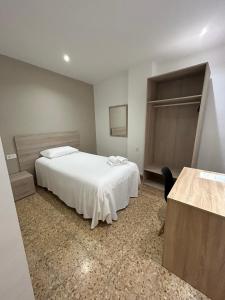 a bedroom with a white bed and a table at Pensión Arnedo in Arnedo