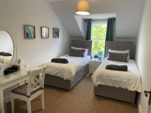 a bedroom with two beds and a desk and a mirror at Luxury town centre stay Ballycastle in Ballycastle