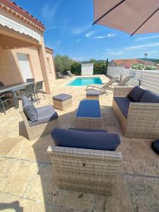 patio z wiklinowymi meblami i basenem w obiekcie GITE CESAR 6p, 3ch, piscine privée, terrain privé clos, terrain de pétanque w mieście Vallon-Pont-dʼArc