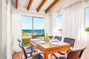a dining room with a table and chairs and the ocean at Villa Romani Arenal by Villa Plus in Arenal d'en Castell