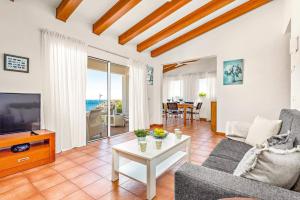 a living room with a couch and a tv and a table at Villa Romani Arenal by Villa Plus in Arenal d'en Castell