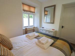 a bedroom with a bed with two towels on it at Rowan Cottage in Grasmere