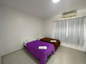 a bedroom with two beds with purple sheets and a window at Pousada Anadia in Cajá