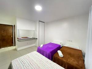 a room with two beds and a purple blanket at Pousada Anadia in Cajá