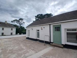 a white building with a green door in a parking lot at Castle Mill Cottages in Wexford