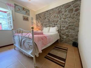 a bedroom with a bed and a stone wall at Casa dos Cabencos in Terras de Bouro