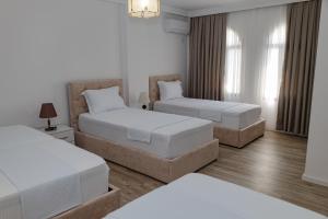 two beds in a room with white walls and wood floors at Riviera Hotel-City Center in Vlorë