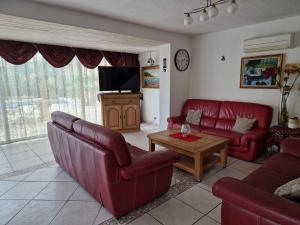 a living room with red couches and a tv at Villa Sambracitaine in Les Issambres