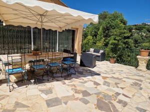 a patio with a table and chairs and an umbrella at Villa Sambracitaine in Les Issambres