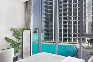 a bedroom with a view of a pool and a building at Exclusive 1BR District 1 - Crystal Lagoon Access in Dubai