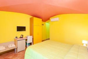 a bedroom with yellow walls and a bed and a desk at B&B Pettirosso Garden in San Teodoro
