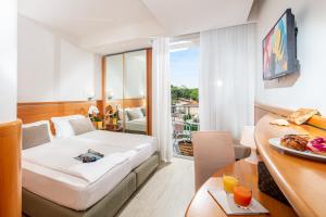 a hotel room with a bed and a table with a plate of food at Park Hotel in Lignano Sabbiadoro