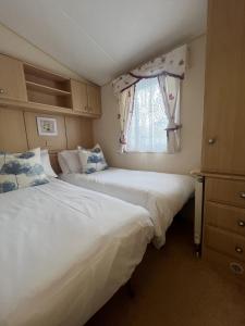 two beds in a small room with a window at Cuddfan in Llanrhystyd