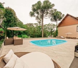 a swimming pool with chairs and an umbrella at Hotel Querência in Gramado