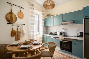 a kitchen with blue cabinets and a table with chairs at Infinite Residences - Central Location, Tradition and Comfort in Corfu Town
