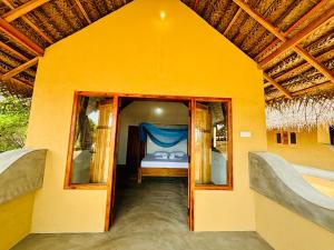 a small yellow room with a bed in it at Peanut Farm Surf and Wild Resort - Arugambay in Arugam Bay