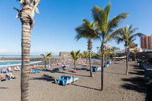 a beach with palm trees and a crowd of people at Apartamento con vistas panorámicas in Puerto de la Cruz