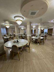 a dining room with tables and chairs and chandeliers at Pensiunea Balea in Cîmpeni