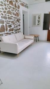 ein weißes Sofa in einem Wohnzimmer mit einer Steinwand in der Unterkunft Suite da Ninna 2 in Allai