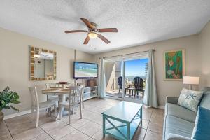 a living room with a ceiling fan and a table at Tradewinds 307 in Orange Beach +27 photos