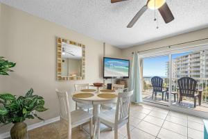 a dining room with a table and chairs and a balcony at Tradewinds 307 in Orange Beach