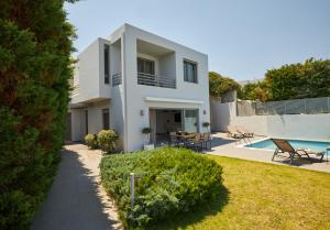 a white house with a yard and a swimming pool at Villa Soligia Thalassa in Pefkali