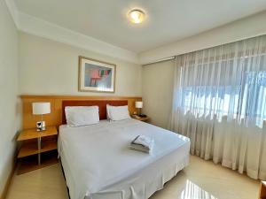 a bedroom with a large white bed and a window at Bienal First Class Flat Service in São Paulo +15 photos
