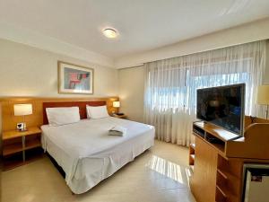 a bedroom with a bed and a flat screen tv at Bienal First Class Flat Service in São Paulo