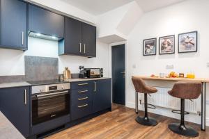 a kitchen with black cabinets and two bar stools at The Tides, 3 bed house Morecambe in Morecambe