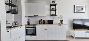 a white kitchen with white cabinets and a tv at Studio Casa Brisa Del Mar in Middelkerke