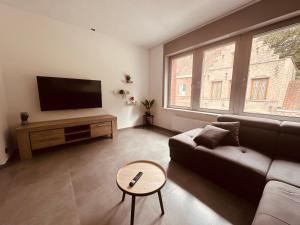 a living room with a couch and a flat screen tv at Woning Meningate in Ieper