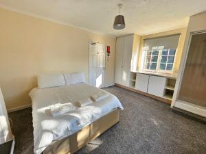 a bedroom with a bed with white sheets and a window at Central Studios 87 Tennyson Road in Cheltenham