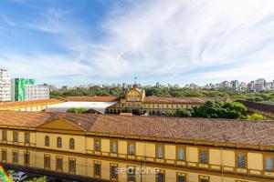 an old yellow building with a city in the background at Studio encantador e bem localizado PoA-RS VENB504 in Partenon