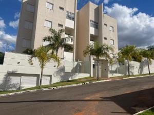 a building with palm trees in front of a street at Apto próximo ao Shopping in Umuarama