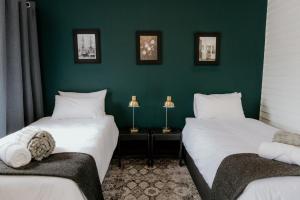 two beds in a room with green walls at Fritz Manor Bed and Breakfast in Swakopmund