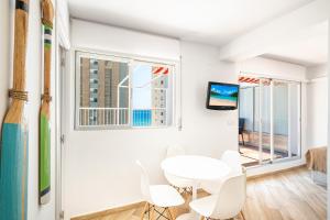 ein weißes Esszimmer mit einem Tisch und Stühlen sowie einem Fenster in der Unterkunft Penthouse El Pato 872 Levante Beach in Benidorm