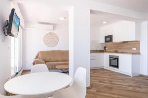 eine weiße Küche und ein Wohnzimmer mit einem weißen Tisch und Stühlen in der Unterkunft Penthouse El Pato 872 Levante Beach in Benidorm + 29 Fotos