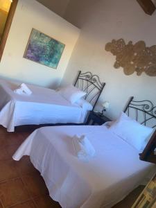 two beds in a hotel room with white sheets at Hosteria La Higuera H-CC-798 in Garrovillas