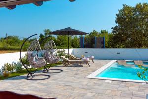 a patio with chairs and an umbrella next to a pool at Villa Meden Dol in Rupe