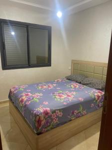 a bedroom with a bed with a purple blanket with flowers at Sablet mohammedia in Pont Blondin