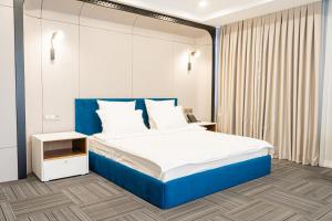 a bedroom with a large bed with a blue headboard at Makhambet Hotel in Shymkent