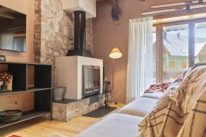 a living room with a fireplace and a stone wall at Luderna - Casa con terraza Somont in Naut Aran