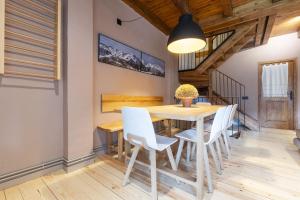 a dining room with a wooden table and white chairs at Luderna - Casa con terraza Somont in Naut Aran