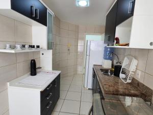 Una cocina con gabinetes negros y un refrigerador blanco. en Vista Maravilhosa, 3 Quartos, Lazer com Piscina, Churrasqueira e 2 Vagas, en Arraial do Cabo 19 fotos más