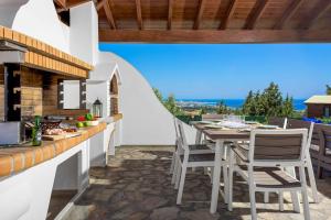 une cuisine extérieure avec une table et des chaises sur une terrasse dans l'établissement Aegean Blue Villa, à Koskinou